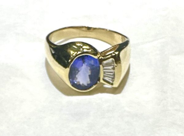 14K Y/G DIAMOND AND TANZANITE FASHION RING CONSISTING OF 0.25 PTS OF BAGUETTES AND AN OVAL TANZANITE MEASURING 9MM X 7MM. 5.7 DWT. SIZE:9.5.